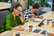 © Friends Stock - Young cheerful asian woman talking by phone and making some notes while working in the modern office