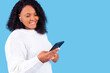 © yurakrasil - african american woman isolated on blue background in studio Listen music with earpods