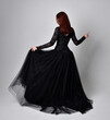 © faestock - full length portrait of  woman wearing black gothic dress,  Standing pose  against a studio background.
