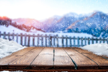 Wall Mural - wooden table in the snow against the backdrop of a mountain landscape at sunset