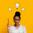 © Prostock-studio - Genius problem solutions. Collage with shocked black woman pointing up at light bulbs over her head, yellow background