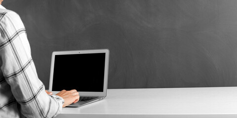 people sits on a work with a laptop computer for a color table on the blackboard background