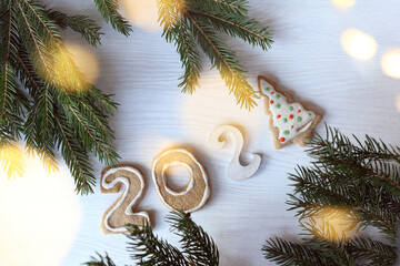 gingerbread cookies in the form of numbers and a Christmas tree on a table with blurry lights. sweet holidays 2021