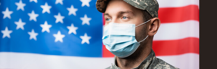 Wall Mural - military man in uniform and medical mask near american flag on blurred background, banner