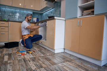 Wall Mural - Young caucasian worker measuring drawer in kitchen furniture