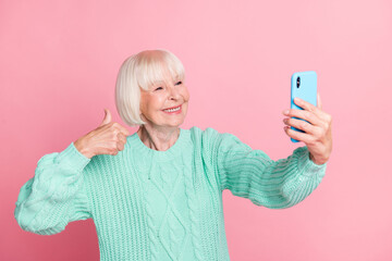 Sticker - Photo portrait of cute granny taking selfie showing thumb-up like sign smiling isolated on pastel pink color background