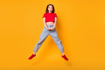 Poster - Photo of shocked jumping lady open mouth wear red crop top jeans shoes isolated yellow color background