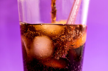 Wall Mural - detail of fizzy and carbonated cola drink on purple background