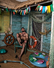 handsome physically well-developed man on the porch of a fishing house near the sea