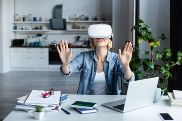 Wall Mural - blonde woman in vr headset gesturing while sitting at table