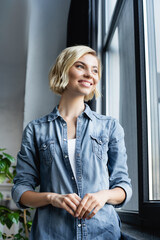 Wall Mural - portrait of smiling woman standing near window