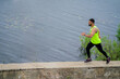 © Georgii - Running guy in stylish sportswear on workout outside in front of water