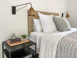 Bed maid-up with clean white and gray pillows and bed sheets in bedroom with small side table and lamp