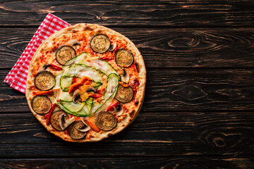 Wall Mural - Vegetable pizza with mushrooms, zucchini and eggplant on a wooden background.