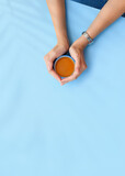 Fototapeta  - Girls hands hold a tea cup on a blue background. Home office desk. Flat lay, top view. Fashion blog look. Add your text.