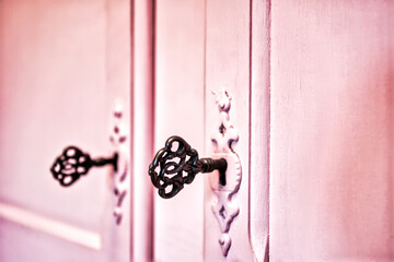 Pink vintage antique doors with old skeleton keys in lock wooden background texture, retro design