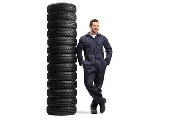 Wall Mural - Full length portrait of an auto mechanic worker leaning on a pile of many car tires