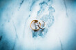 A pair of gold and white gold wedding rings on a blue marble background