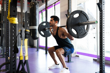 Young man doing a squat and lifting weights