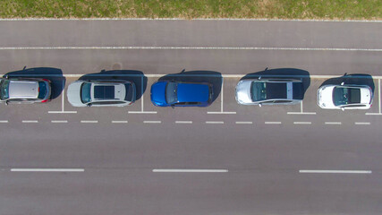 TOP DOWN: Flying above row of cars neatly parked in their roadside parking space