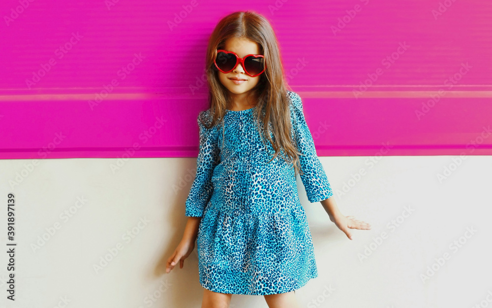 Portrait of beautiful little girl child wearing a blue dress over pink ...