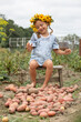 © Angelina - cute little girl in a wreath of yellow flowers sits on a potato field