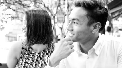 Poster - Young asian couple relaxing outdoor at a restaurant table