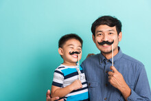 Family Funny Happy Hipster Father And His Son Kid Holding Black Mustache Props For The Photo Booth Close Face, Studio Shot Isolated On A Blue Background, November Men Health Awareness