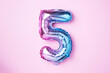 Creative layout. Rainbow foil balloon number and digit five 5. Birthday greeting card. Anniversary concept. Top view. Copy space. Stylish colored numeral over pink background. Numerical digit.