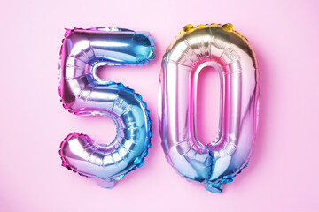 Rainbow foil balloon number, digit fifty. Birthday greeting card with inscription 50. Anniversary concept. Top view. Colored numeral on pink background. Numerical digit, Celebration event, template