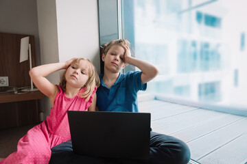 Wall Mural - kids bored with computer at home, boy and girl stressed and exhausted