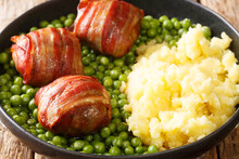 Delicious Meatballs Wrapped In Bacon Garnished With Green Peas And Mashed Potatoes Close-up In A Plate On The Table. Horizontal