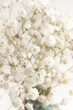 Bouquet gypsophila white tiny flowers with colorful blue vase and ribbon macro retro style