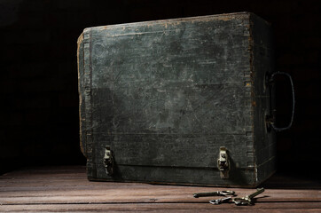 Closed old wooden chest and bunch of keys on the rustic surface against dark background