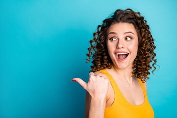 Poster - Photo of lovely ginger young lady direct thumb empty space excited look open mouth wear yellow singlet isolated blue color background