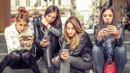  Group of girls using smartphones outdoor, having fun with technology trends. Youth, new generation addiction and friendship concept. Internet lifestyle generation