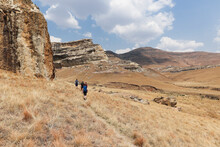 Hikers Walking In The Golden Gate National Park Along A Path In Single File Towards The Sandstone Mountains.