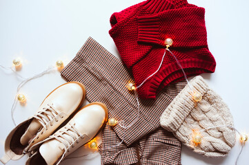 Wall Mural - Online Christmas shopping and sale concept. Flat lay of woman fashion clothes in red and beige tones. Shoes, sweater, warm hat and scarf.