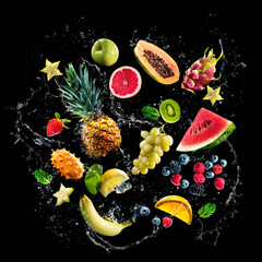 Assortment of fresh fruits and water splashes on black background