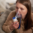 woman makes inhalation nebulizer at home. holding a mask inhaling fumes spray the medication into your lungs sick patient. self-treatment of the respiratory tract using inhalation nebulizer