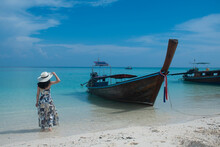 Woman Tourist Stand Beside Traditional Thai Wooden Longtail Boat On The Shore Of Bamboo Island, Krabi Province