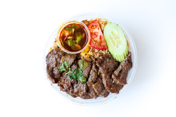 Wall Mural - Asian dish prepared with beef pieces, tomatoes and cucumber slices on top of fried rice served in a bowl, for an healthy and complete meal