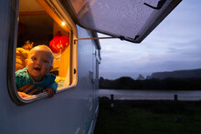 Baby At Window Of Motorhome In The Evening During Road Trip.