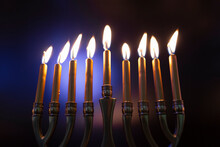 Lit Menorah In Celebration Of Hanukah Against Colored Background