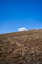 Looking Up Hill With Brown Grass To Cloud In Blue Sky In California