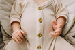 © Cavan Images - Close up of a big full baby belly in cream colored outfit with buttons