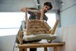 © Cavan Images - Low angle view of a man repairing and restoring an old chair