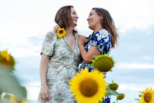 Mother And Daughter Hugging And Kissing In A Field Of Sunflowers