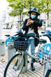 © Cavan Images - Young woman with mask chooses bicycle at a public rental point