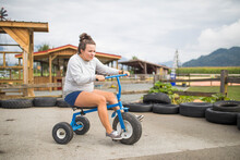Fun Expectant Mother Riding Oversized Tricycle On Race Track.